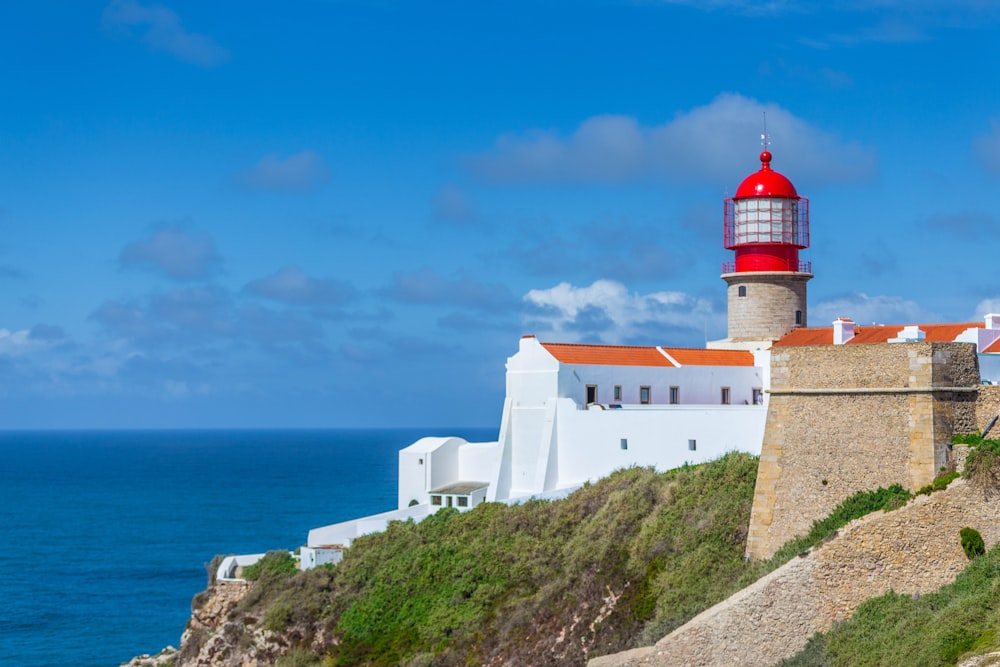 white, red, and brown lighthouse by the sea during daytime