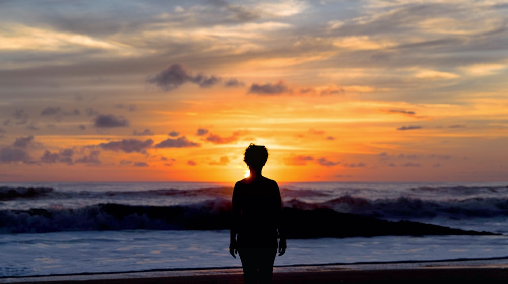 silhouette of woman standing near seashore