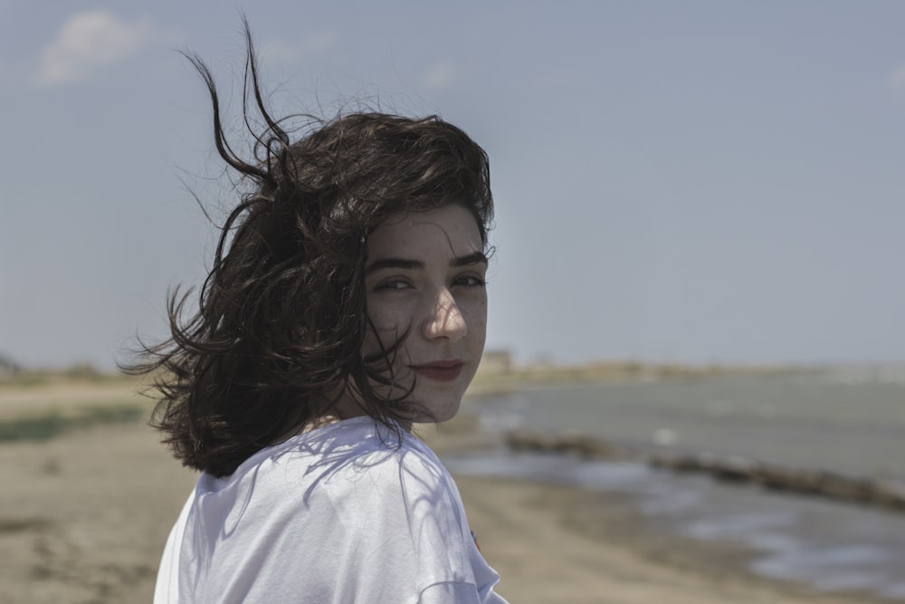 woman wearing white top standing near body of water