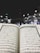 An open Quran is prominently displayed, with Arabic text visible on both pages. The background features an outdoor setting at night, with the Kaaba surrounded by worshippers wearing white clothing, indicative of a religious gathering.