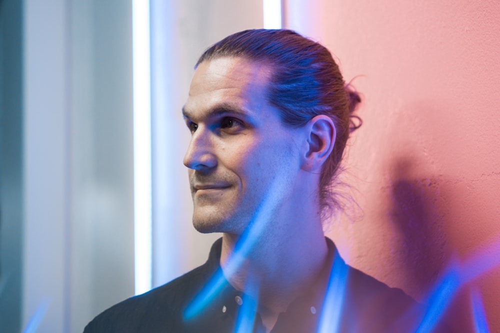 man in black collared shirt leaning near wall