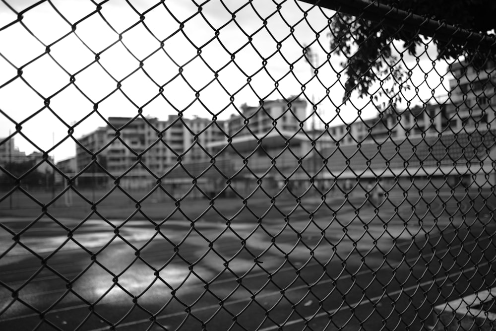 grayscale photography of an open court with wire fence