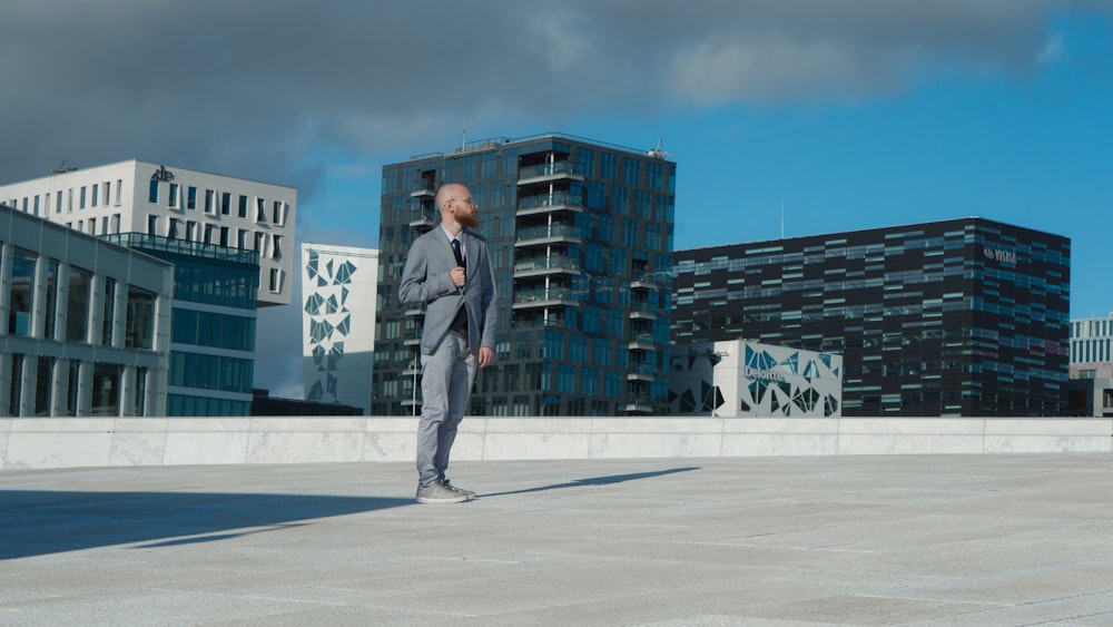 man standing in an open field with concrete buildings background