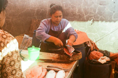 Skilled worker carefully cutting fresh fish with a sharp knife in a clean processing area.