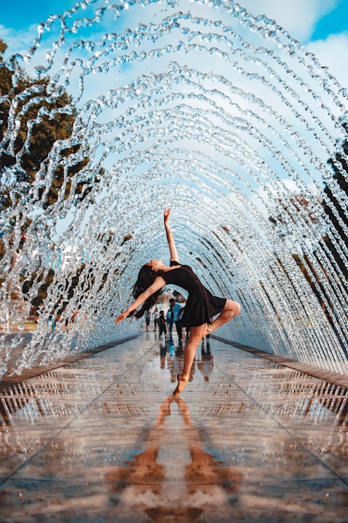 woman in black flare dress under water fountain