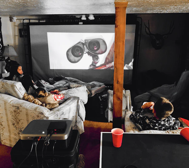 A cozy home cinema setup with a projector and movie posters on the wall.