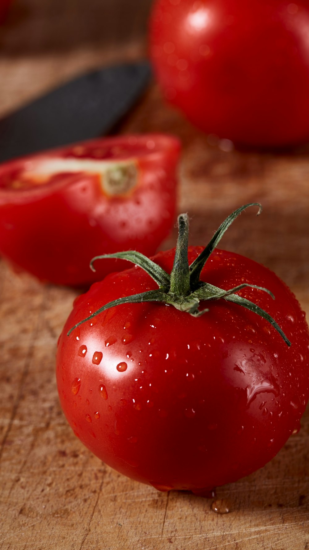 スライスした赤いトマトの横に2つの赤いトマト