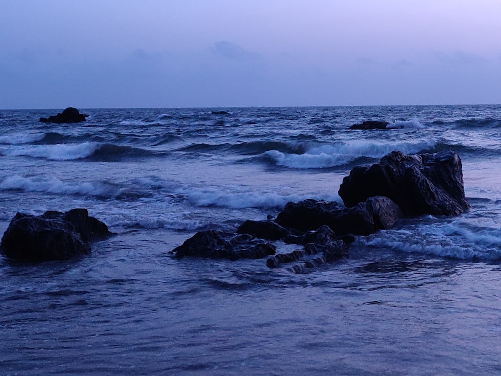 sea waves crashing on rocks during daytime
