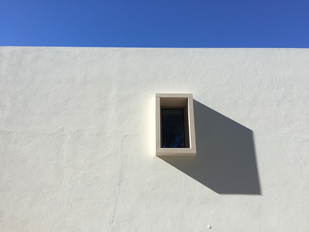 un muro bianco con una finestra e un cielo blu