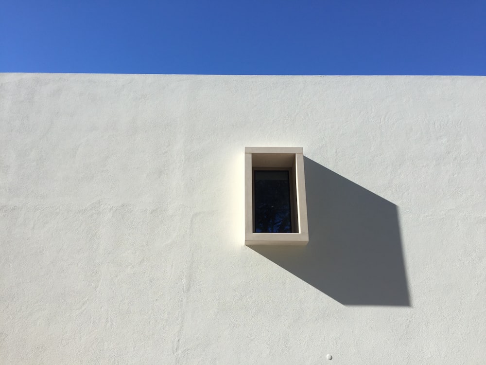 a white wall with a window and a blue sky