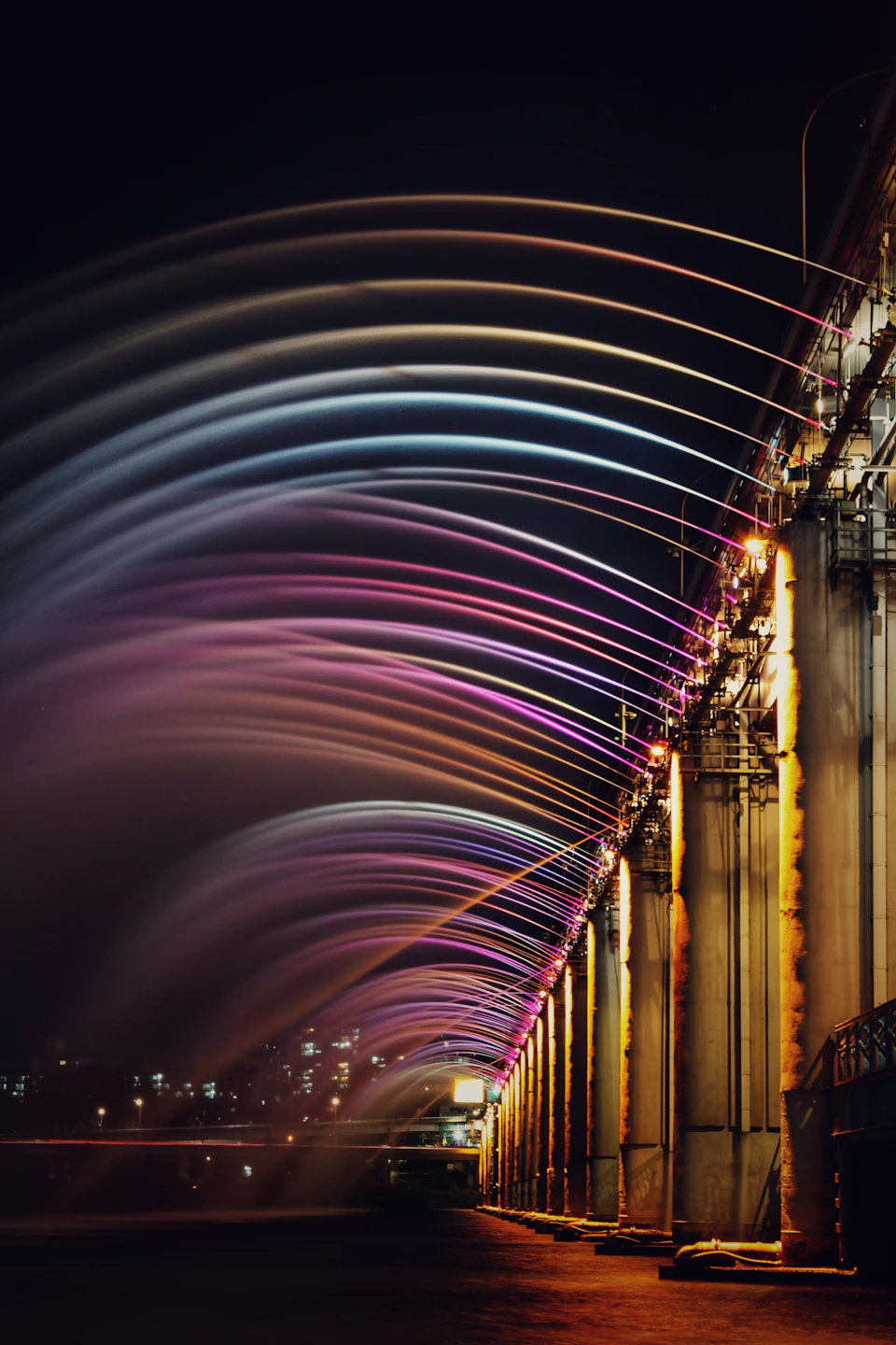 Vibrant night scene at train station with illuminated columns and colorful lights lining tracks