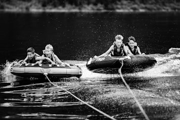 four children riding inflatable rafts pulled by motorized boat