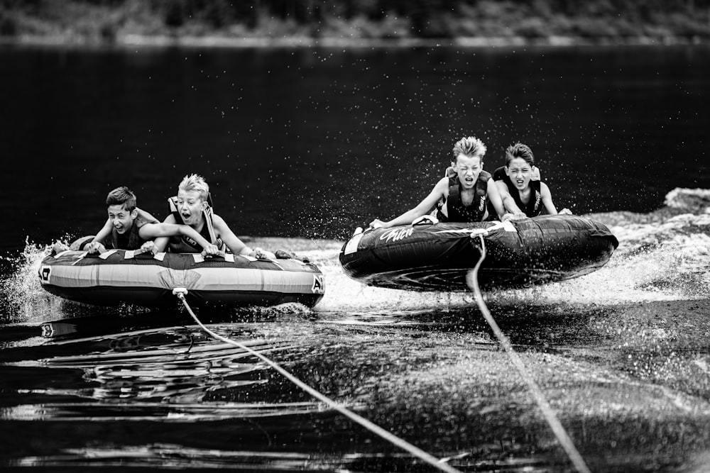 vier Kinder auf aufblasbaren Flößen, die von einem Motorboot gezogen werden