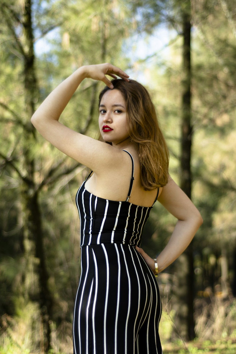 woman wearing black and white striped jumpsuit standing near trees