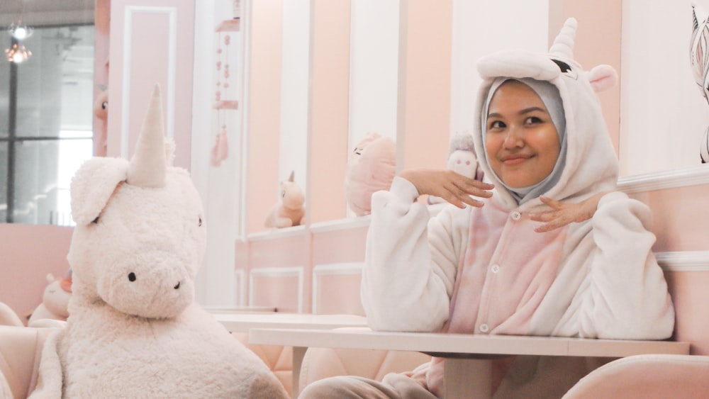 woman wearing white-and-pink unicorn costume sitting chair