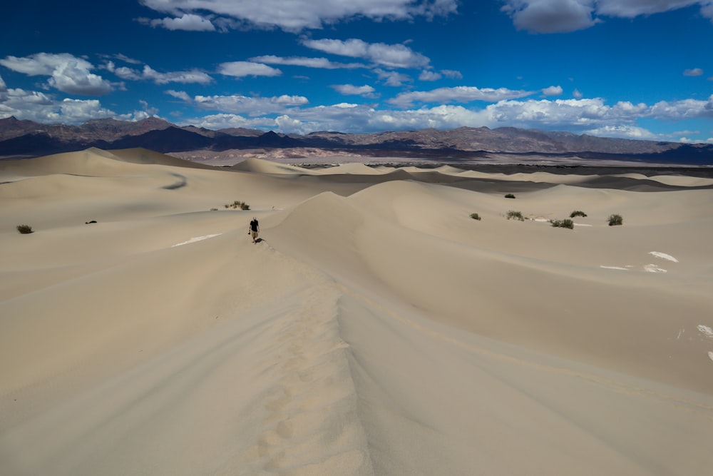 person standing on deserted place under blue and white skies