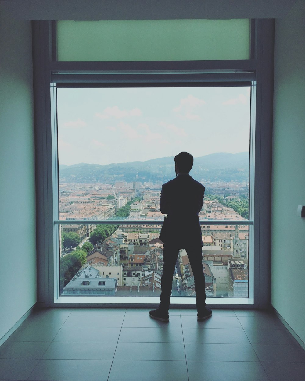 man standing near glass railing looking outside