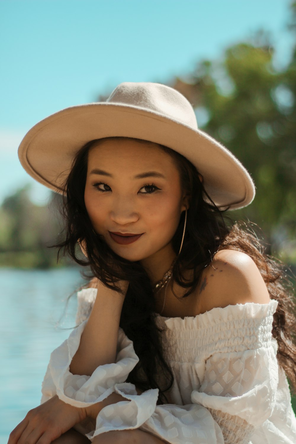 woman in white off-shoulder shirt and beige hat