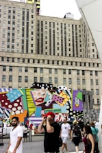 A lively street mural being painted with bold pop art colors and designs.