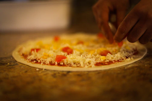 Chef finishing pinsa with fresh toppings in a restaurant kitchen.