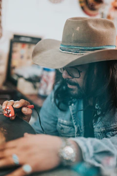 Close-up of a master artisan hand-stitching a rich leather cowboy hat under warm studio lighting.