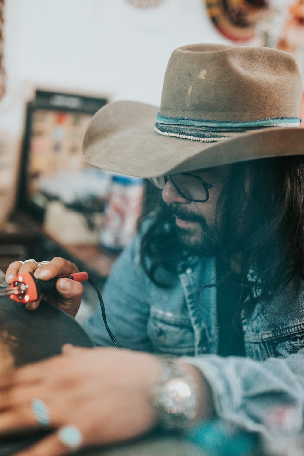 man in blue denim jacket and brown stetson hat