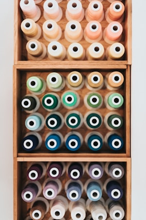 Close-up of colorful sewing notions like buttons, zippers, and ribbons neatly arranged on a wooden table.