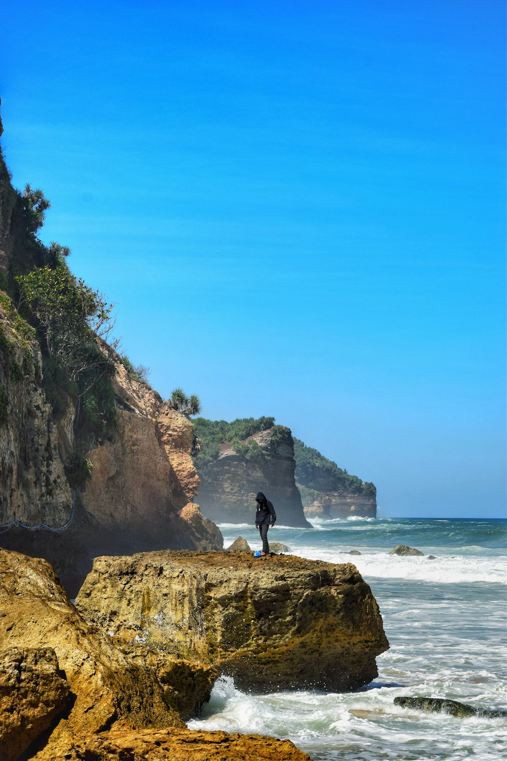 man standing on rocky island shore during day