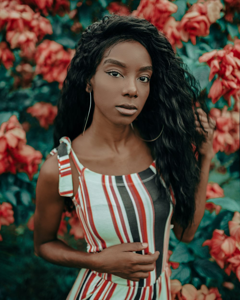 woman holding hair standing near red flowers