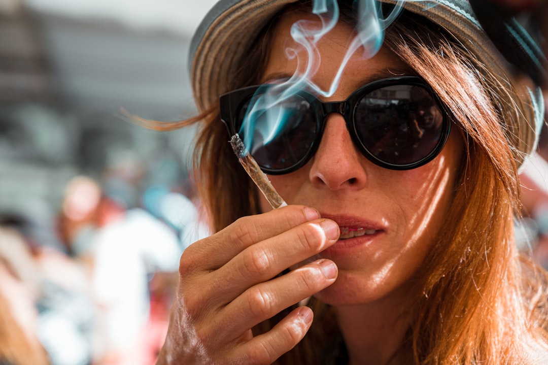woman wearing black frame sunglasses smoking during daytime