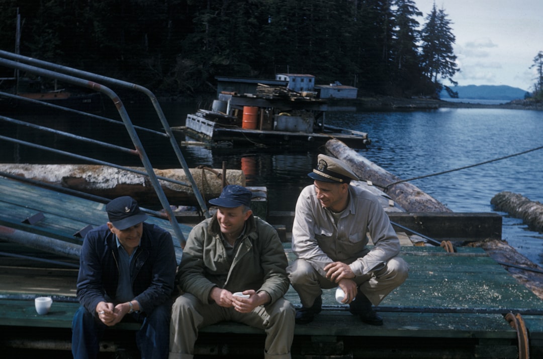 three men sitting on dock