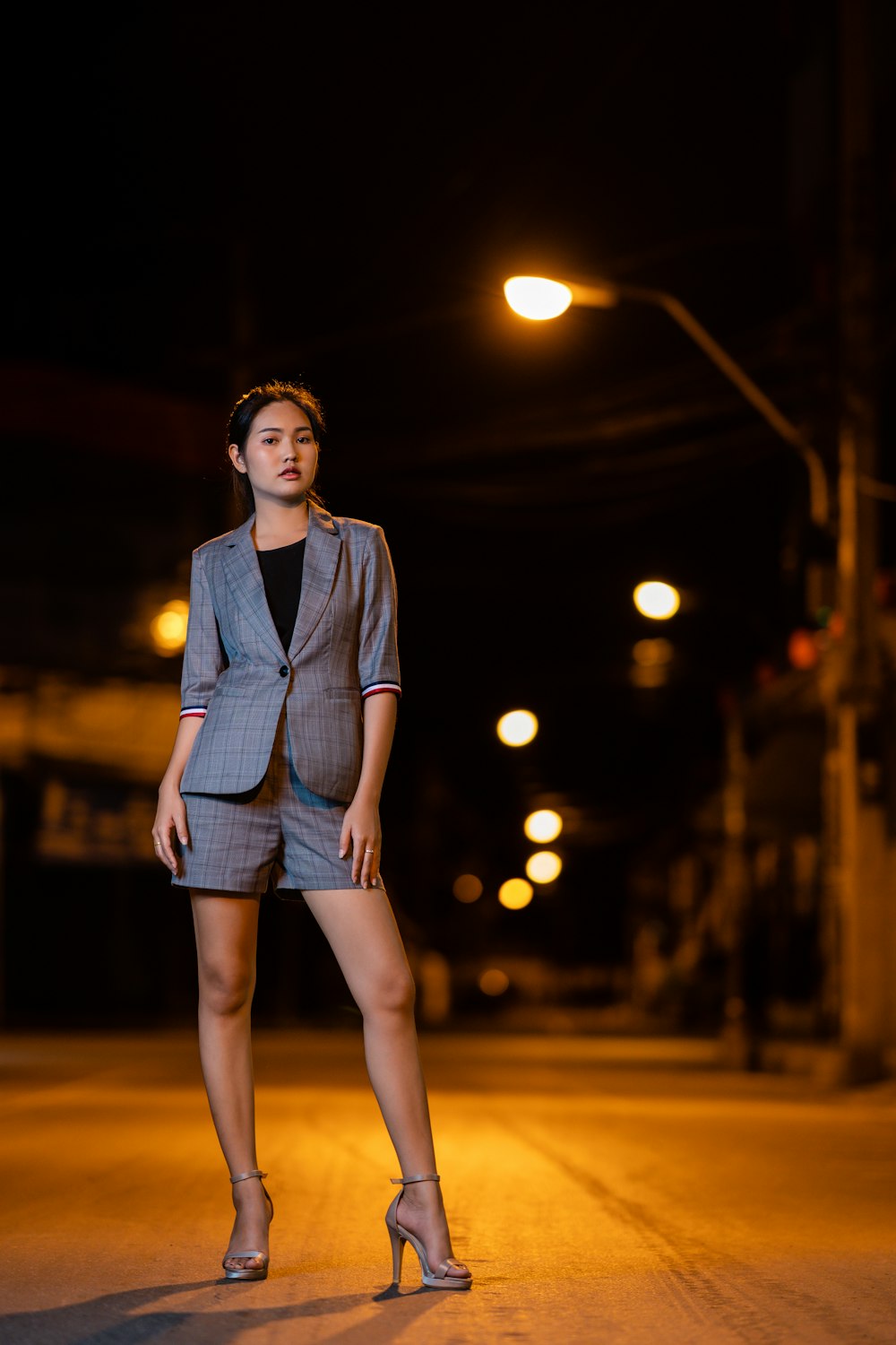 woman in in gray suit standing on street during nighttime