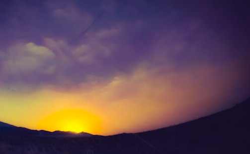 Vibrant travel vlog still capturing a sunset over a mountain range.