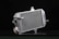 A metallic car radiator is placed against a dark background, highlighting its shiny silver surface and intricate grid of cooling fins. The radiator has several metal connectors protruding from its sides, and a cap with a caution label is visible in the lower area.