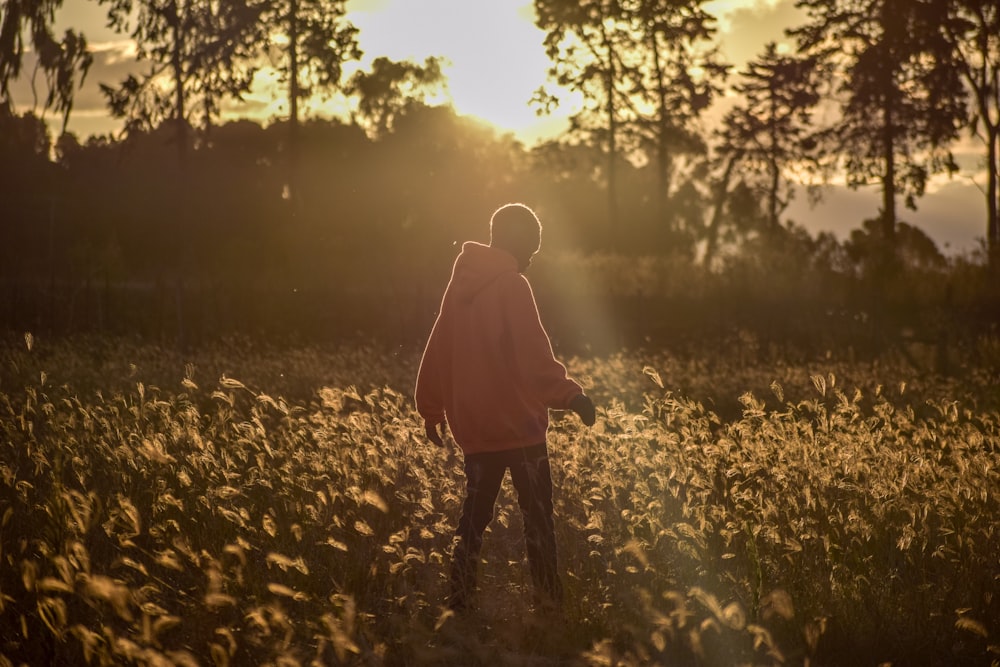 person in beige hoodie and blue denim jeans in grass field