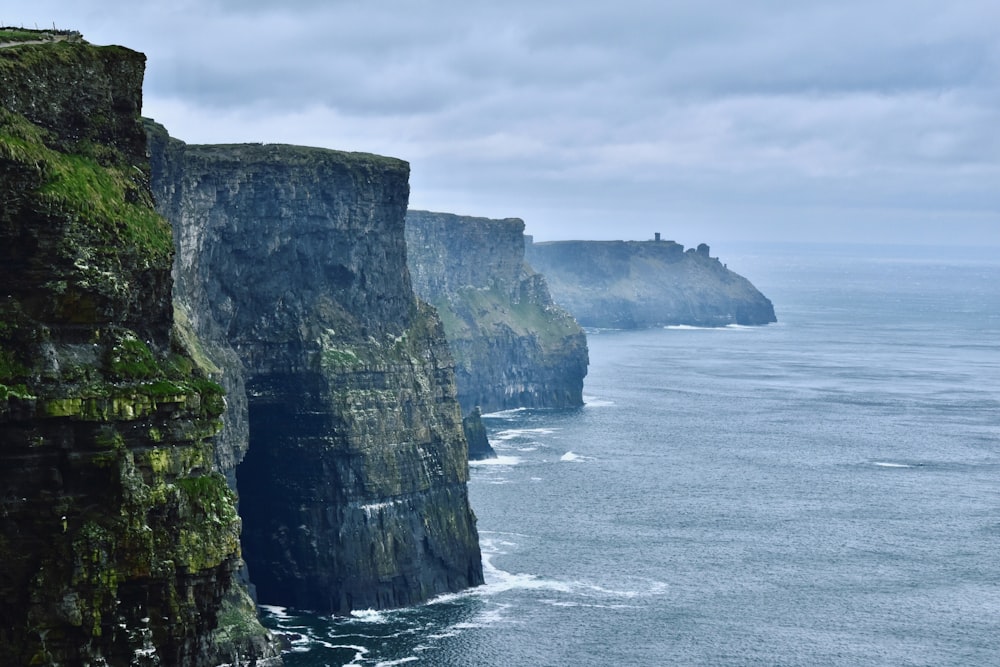 photography of mountain cliff beside seashore during daytime