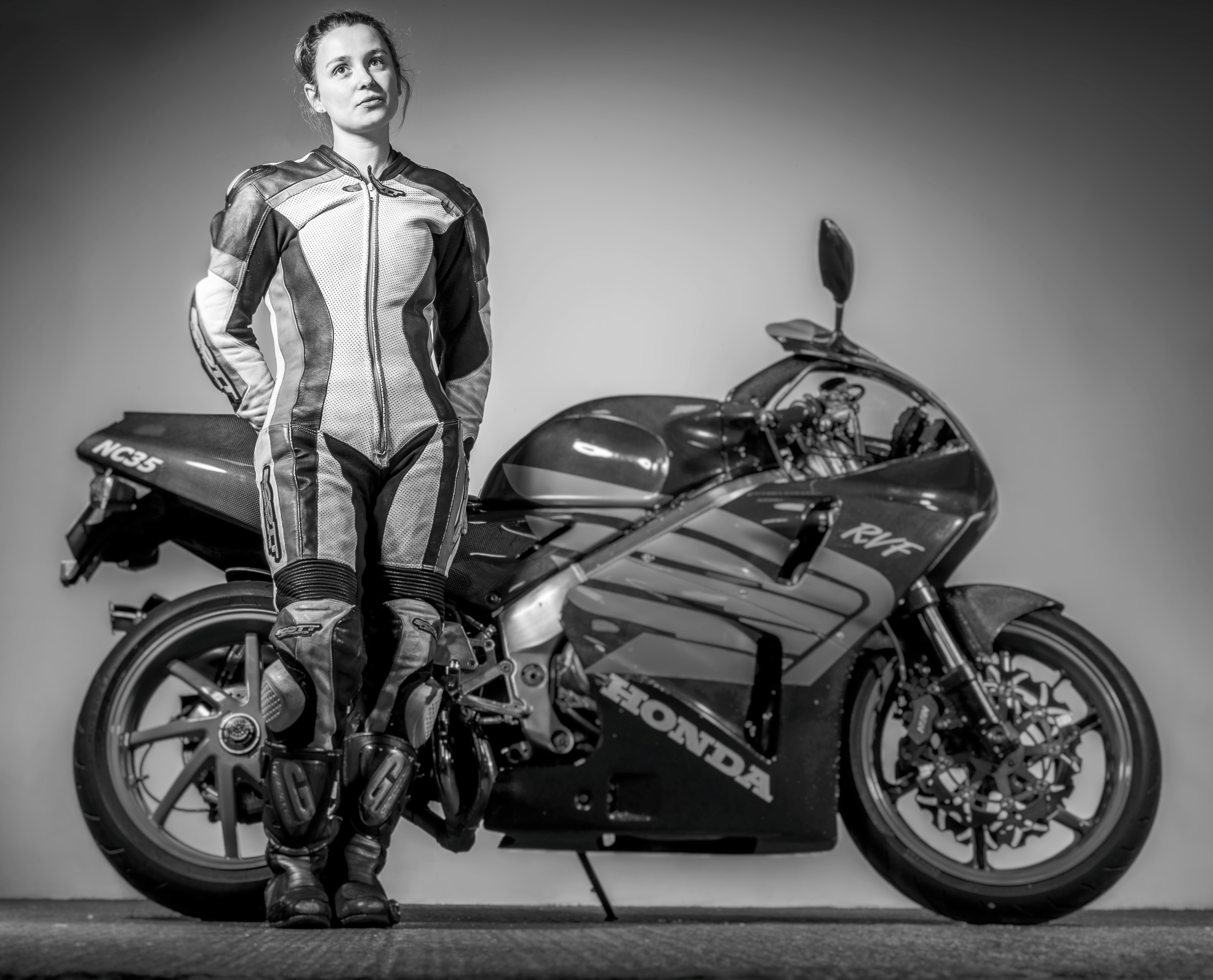 grayscale photo of a woman beside a motorcycle