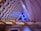 An intricate interior architecture design featuring a series of interlocking geometric patterns. The ceiling displays layers of semi-circular shapes in pastel colors, accented by green and blue lighting elements. The space is lit with ambient lighting, enhancing the modern and futuristic aesthetic.