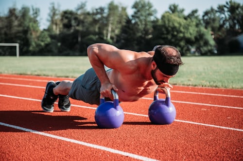The athlete does kettlebell push-ups