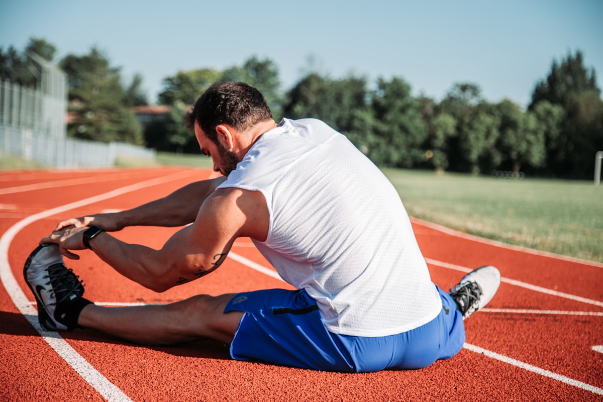 Athlete doing morning stretches for back pain on a running track