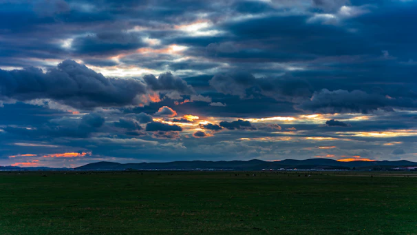 A rugged landscape at dawn with a lone cowboy silhouette overlooking vast open plains.