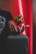 Close-up of hands expertly twisting a bright Rubik's cube against a cozy background.