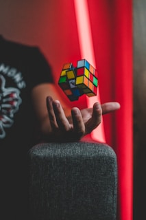 Hands twisting a vibrant Rubik's cube under warm lighting, showing focus and fun.