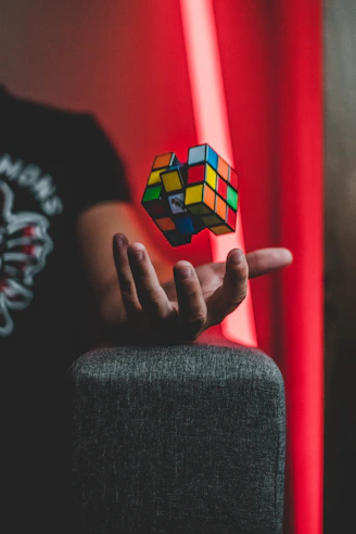 A colorful Rubik's cube mid-solve with hands gently twisting it on a bright wooden table