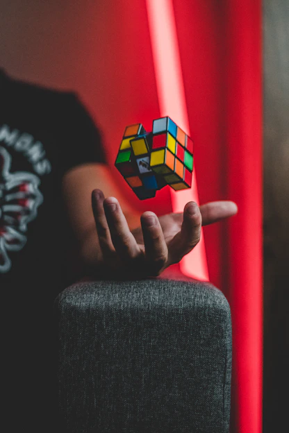 A colorful Rubik's cube mid-solve with hands gently twisting it on a bright wooden table