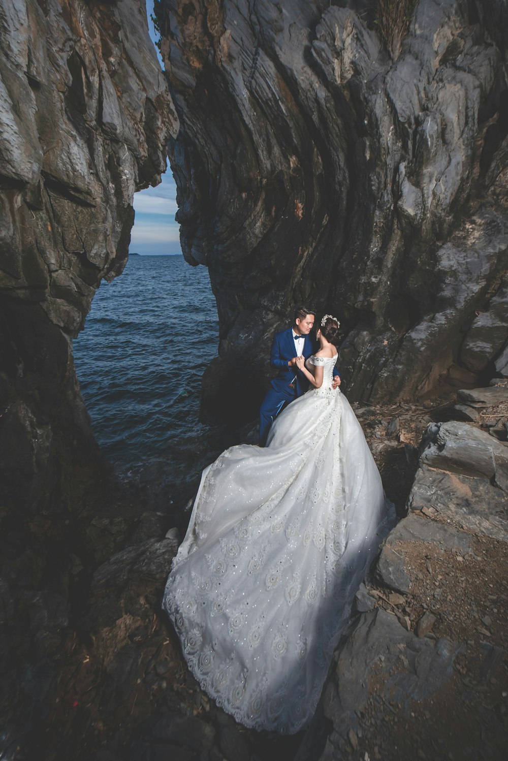 man and woman in wedding dress standing near shore