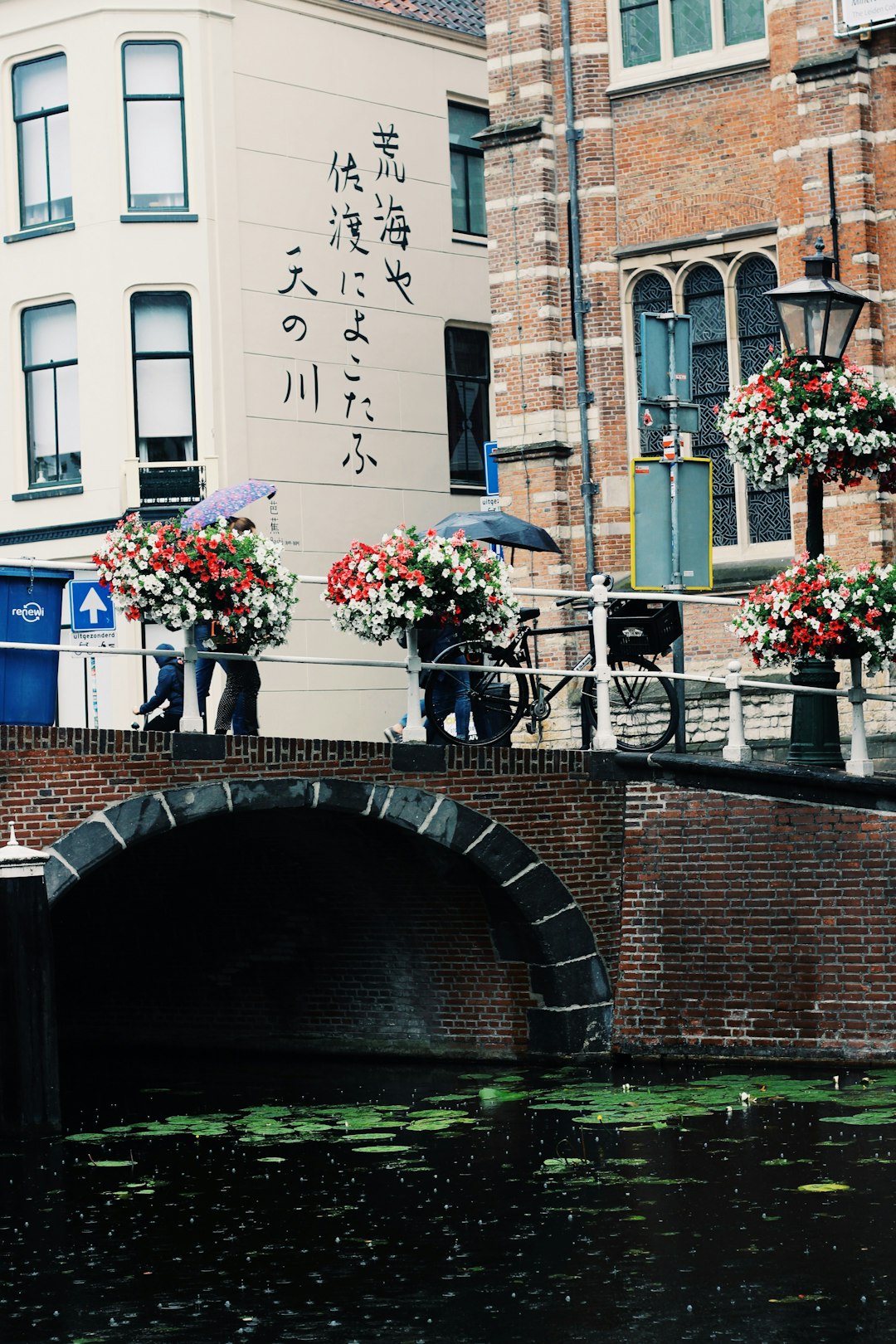 two person with umbrellas walking on concrete bridge