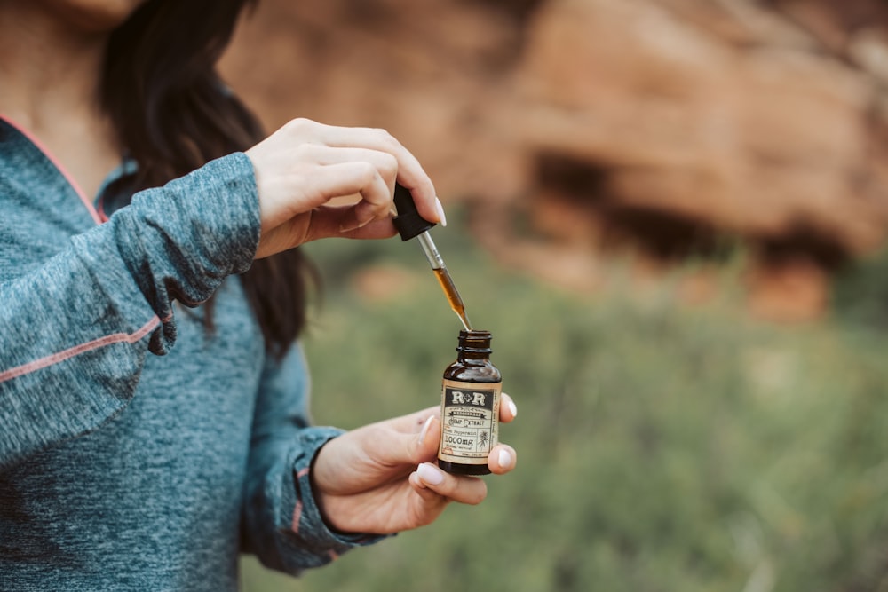 femme tenant une bouteille de gouttelettes de R & R