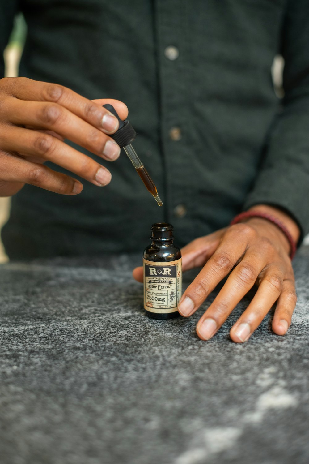 a person with their hand on a table with a bottle of medicine