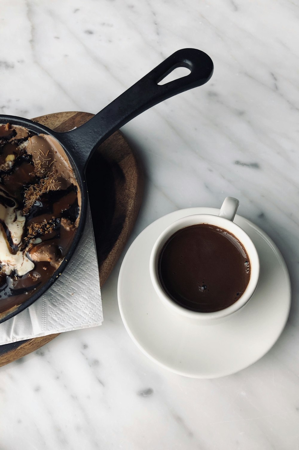 a bowl of ice cream next to a cup of coffee